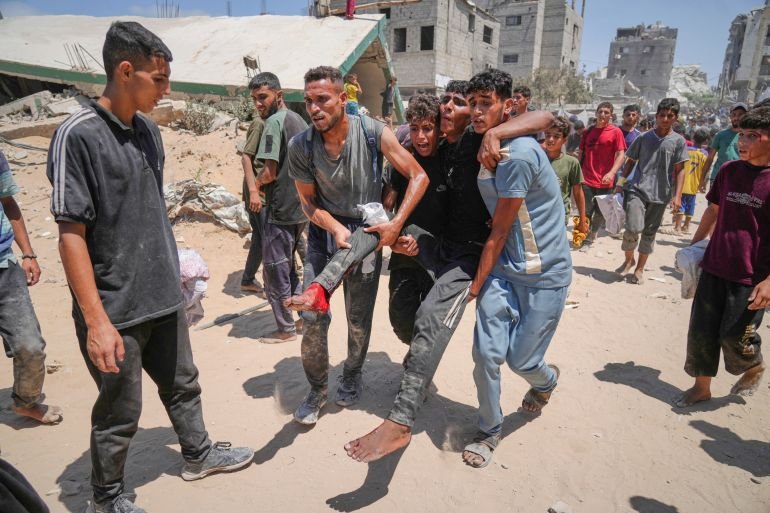 Palestinians carry a wounded man who was injured while rushing to collect humanitarian aid airdropped by parachute into Gaza City, in the northern Gaza Strip, Thursday, Aug. 7, 2025. (AP Photo/Jehad Alshrafi)