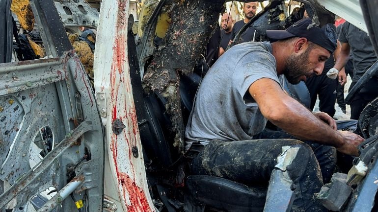 Palestinians inspect a vehicle where media reporter Ismail al-Ghoul and cameraman Ramy El Rify were killed in an Israeli strike