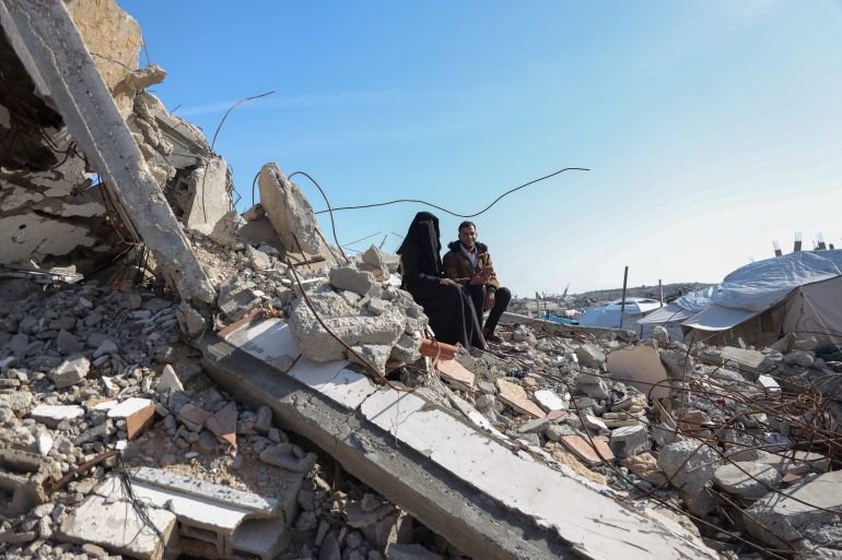Mustafa and Nesma sit on the rubble of the building that was shelled 