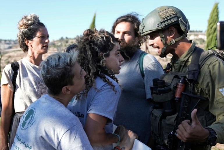 Israeli activists surround Alice Kisiya, center, as they try to enter her family's land, after the Palestinian family was forcefully evicted by Israeli settlers backed by soldiers who declared it a closed military area, in the West Bank town of Beit Jala, Friday, Aug. 2, 2024. (AP Photo/Mahmoud Illean)