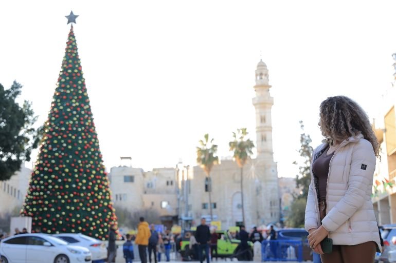 Alice Kisiya stands in front of a Christmas tree