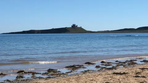 David Land A landscape photo of a sandy beach, sea and land with some brick ruins