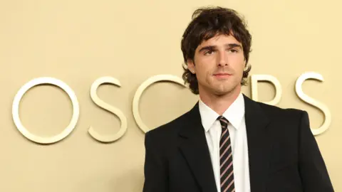 Reuters Jacob Elordi in a suit in front of an Oscars sign