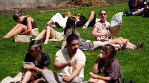 PA Media People sunbathing near St Paul's Cathedral in London