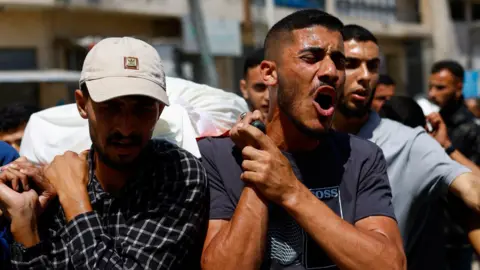 Reuters Mourners carry bodies identified by mourners as Hamas's military wing commander Mohammed Odeh, his wife, and their son, during a funeral in Gaza City, northern Gaza (27 May 2026)