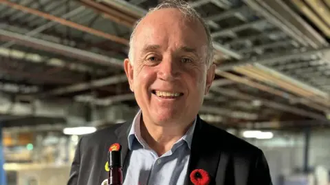 Courtesy of Phillips Distilling Company An image showing Andy England smiling. He is wearing a black suit jacket with a red poppy on the collar.
