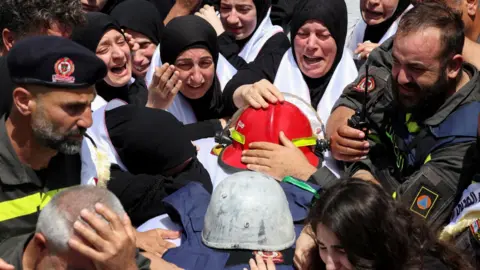 Reuters Mourners attend the funeral of Lebanese Civil Defence paramedics Hussein Jaber and Ahmed Noura, who were killed in an Israeli air strike, in Sidon, southern Lebanon (13 May 2026)