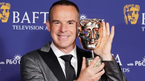PA Media Martin Lewis holding up his trophy at the Bafta TV Awards