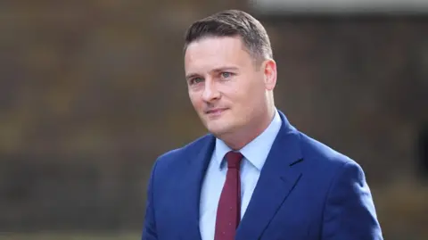 PA Media Health Secretary Wes Streeting arriving at number 10 Downing Street on 13 May, wearing a blue suit and a red tie.