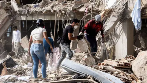 Diko Betancourt/Anadolu via Getty Images Family members and volunteers search through the rubble after two 17-story buildings in the Belo Horizonte residential complex collapsed in Catia La Mar, La Guaira (Venezuela), on June 26, 2026.