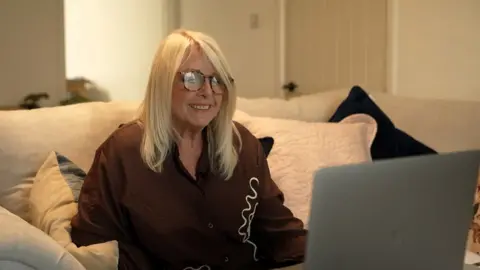 A woman smiles at a computer