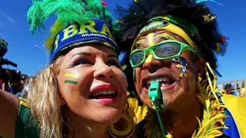 Getty Images A close-up shot of two Brazil fans wearing green and yellow clothes, as well as feather headdresses.