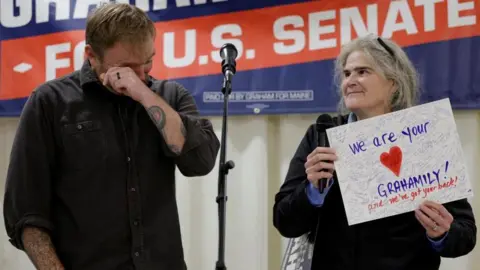 Reuters Graham Plater wipes tears away from his eyes as a supporter holds up a card that reads "We are your Grahamily! and we've got your back!"