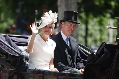 Getty Images The Duchess of Edinburgh and Vice-Admiral Sir Tim Laurence wave from a black carriage.