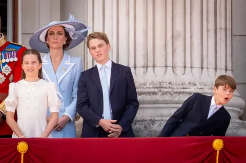 PA Media Prince Louis leans over to his left with his mouth agape as he watched the Red Arros flypast. The Princess of Wales, Princess Charlotte and Prince George stand to his right.