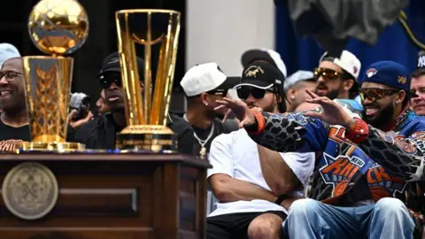 REUTERS/Dylan Martinez General view of the NBA Cup and the Larry O'Brien Championship Trophy as New York Knicks' Karl-Anthony Towns and New York Knicks' Jalen Brunson look on at New York City Hall during the parade 
