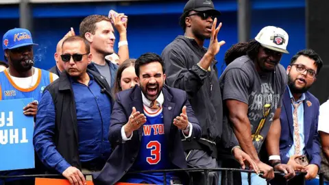 Getty Images Mamdani smiling and laughing from a parade float