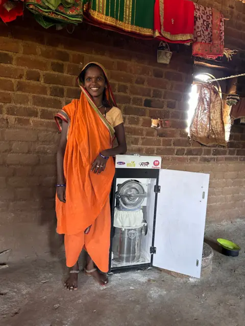 ProjectDEEP Shobha a beneficiary of a lump sum crash transfer program pictured in Shelkui village in Maharashtra, standing with a flour grinder. She often had to travel long distances just to get wheat milled into flour. To overcome this challenge, she invested in a small flour mill of her own with the money and started a business. 