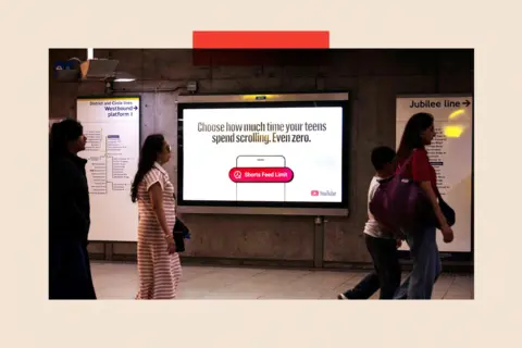 Reuters A YouTube advert at Westminster Underground station in London reads: "Choose how much time your teens spend scrolling. Even zero." Below that is the outline of a mobile phone and an image of a red notification that reads: "Shorts feed limit" alongside an icon of a clock. The YouTube logo is also visible on the advert. Strolling past are three women and a boy.  Maps of the westbound District and Circle lines and the Jubilee line are also visible.