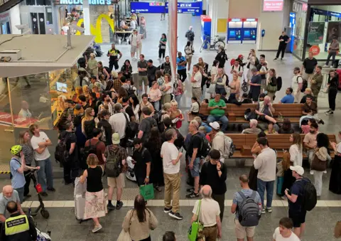 EPA Passengers queue at the Deutsche Bahn service point in the arrivals hall at the main station in Bremen, Germany, 23 June 2026.