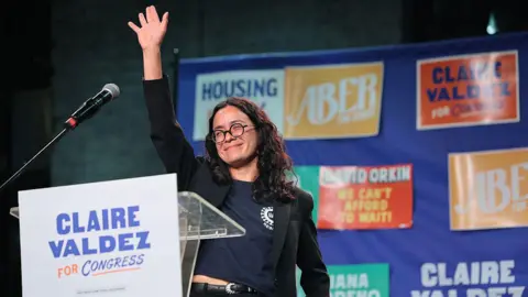 Getty Images Claire Valdez holds her arm up. 