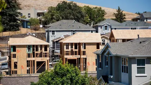 Getty Images A row of houses under construction, some are more finished than others. 