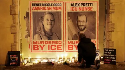 Reuters Posters of Alex Pretti and Renee Good's faces, saying "Murdered by ICE", with candles placed on the ground