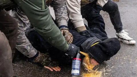 Getty Images three agents pin someone to the ground and spray chemical irritant directly into their face