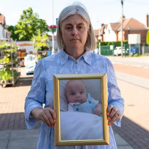 BBC/Chris Waring Michelle Welsh holds a framed picture of her son