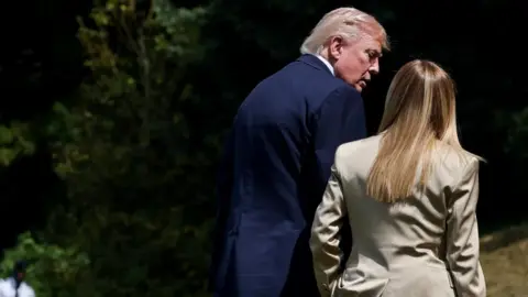 Reuters A man in a blue suit talks with his back to the camera to a woman with blonde hair and a beige suite, again with her back to the camera