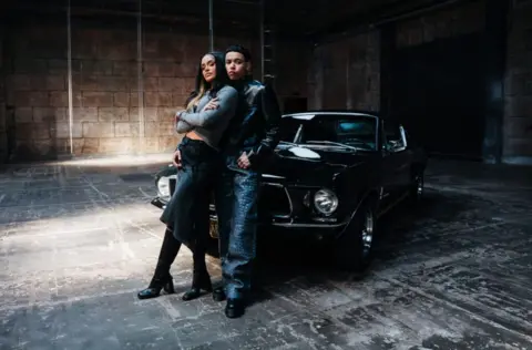RCA Records KWN and Kehlani lean against a black Ford Mustang, on the set of the video for Worst Behaviour.