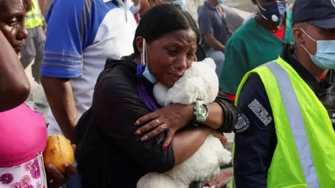 Reuters A woman hugs a teddy bear and cries in a crowd