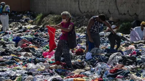 EPA Four people looking through donated clothing which is piled all around them