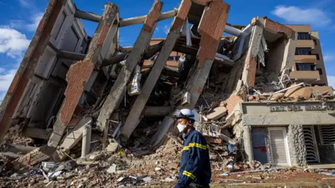 EPA A rescuer walking past the rubble of destroyed buildings in La Guaira 