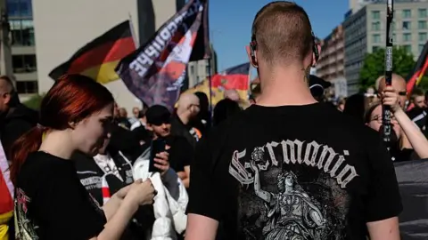 Getty Images Young neo-Nazis with German flags, including one young man with a black t-shirt that reads: "Germania", wait to be allowed by police to resume a demonstration in Berlin last year.