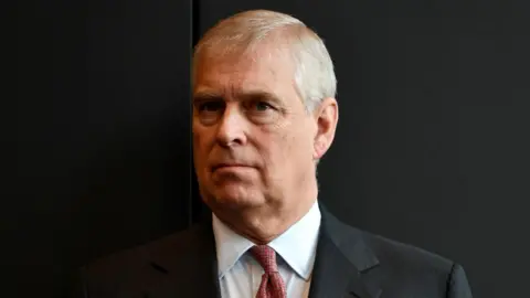 DAVID MARIUZ / EPA head and shoulders picture of Andrew Mounbatten-Windsor against a black background, he wears a suit and red tie, taken in Australia in 2018.
