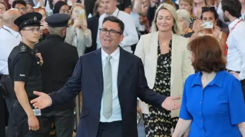 PA Media Andy Burnham opens his arms wide with MPs looking on behind him