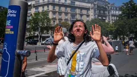 Annice Lyn/Getty Images People cool off beneath a misting station during hot weather on June 24, 2026 in Paris, France.