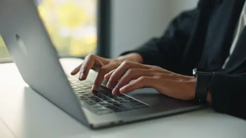 Getty Images A man's hands seen typing on a laptop keyboard