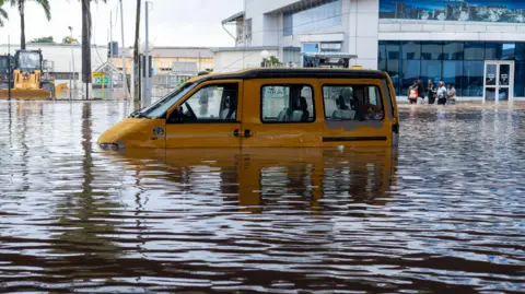 EPA A yellow van half-submerged in floodwater