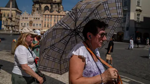 EPA A woman with an umbrella shields herself from the sun in Prague's Old Town 