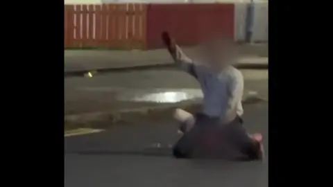 Social Media A image of a man with his hand up in the air. His face is blurred. 
