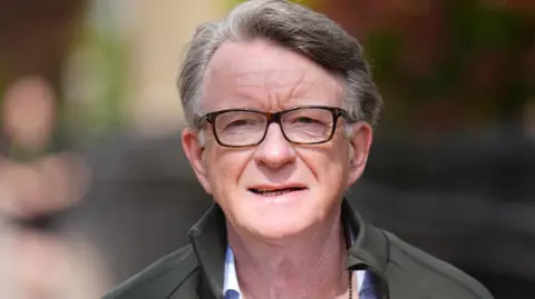 PA Media Peter Mandelson wearing glasses, and an open necked shirt and jacket 