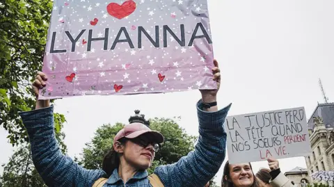 AFP via Getty Images A woman holds up a sign saying "Lyhanna" with hearts surrounding it, during a protest in Paris, France on 8 June.
