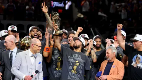 Gregory Shamus/Getty Images Jalen Brunson #11 of the New York Knicks lifts the Bill Russell NBA Finals Most Valuable Player Award trophy after defeating the San Antonio Spurs in Game Five  

