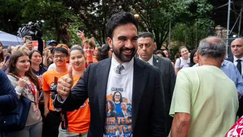 Bloomberg via Getty Images Mamdani shows a thumbs up as he smiles, surrounded by supporters. 