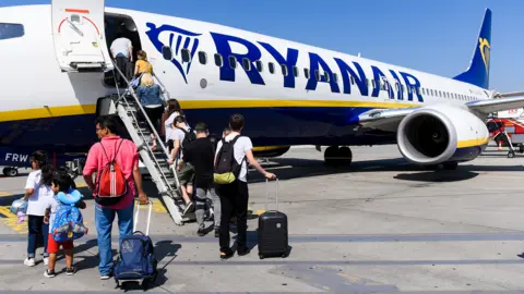 Getty Images Passengers incluidng children boarding a Ryanair aircraft using the steps at the front of the plane on a sunny day with blue skies