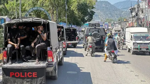AFP via Getty Images Security personnel in a police vehicle patrol a busy road in Muzaffarabad