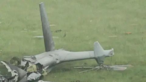 BBC The tail of a grey military helicopter which has crashed in a field in Devon