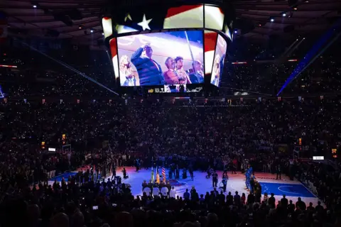 AFP via Getty Images Trump is shown saluting on the jumbotron screen in the middle of the arena, leading to loud boos. 